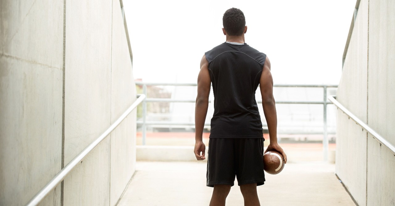 Man with a football standing just outside the entry tunnel
