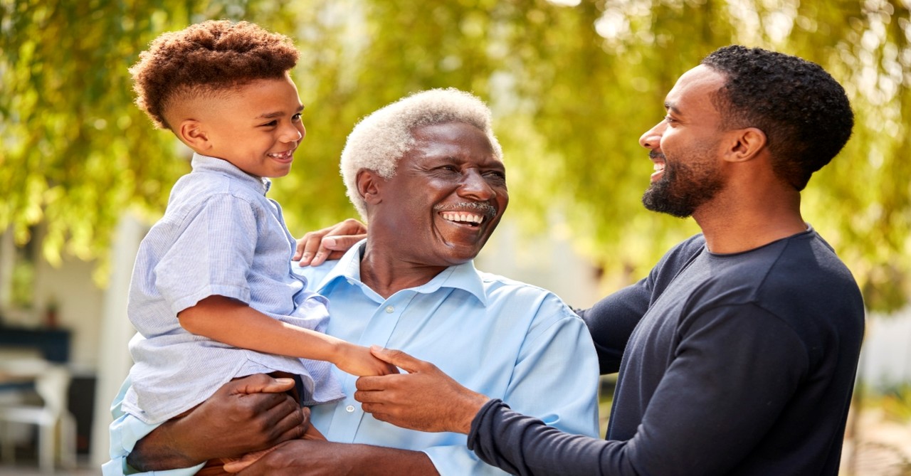 Grandfather holding grandson while son smile