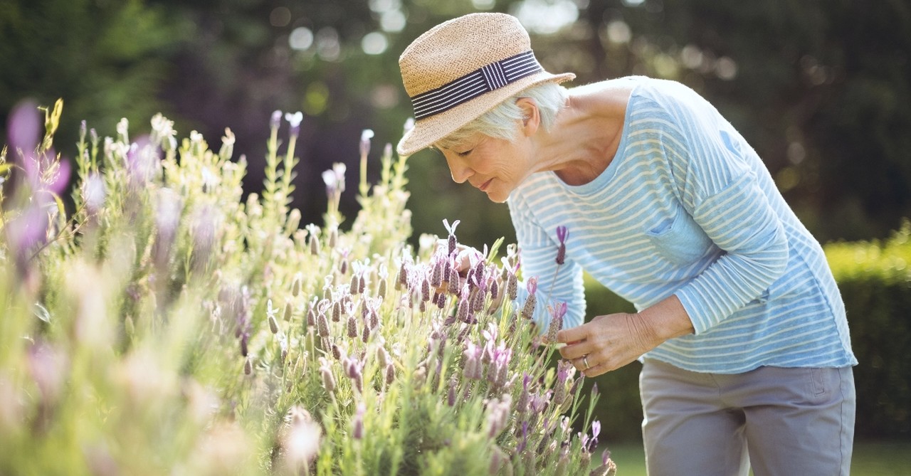 Older woman smelling flowers in her garden