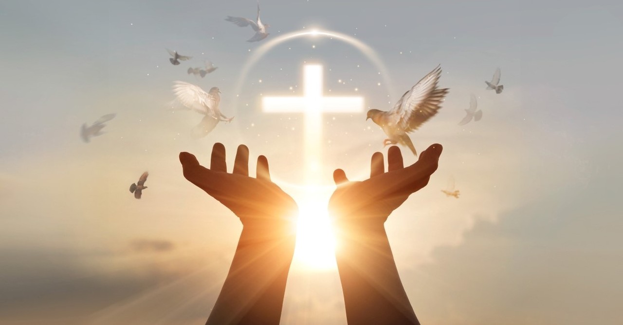 hands held toward sky with cross and birds in sky