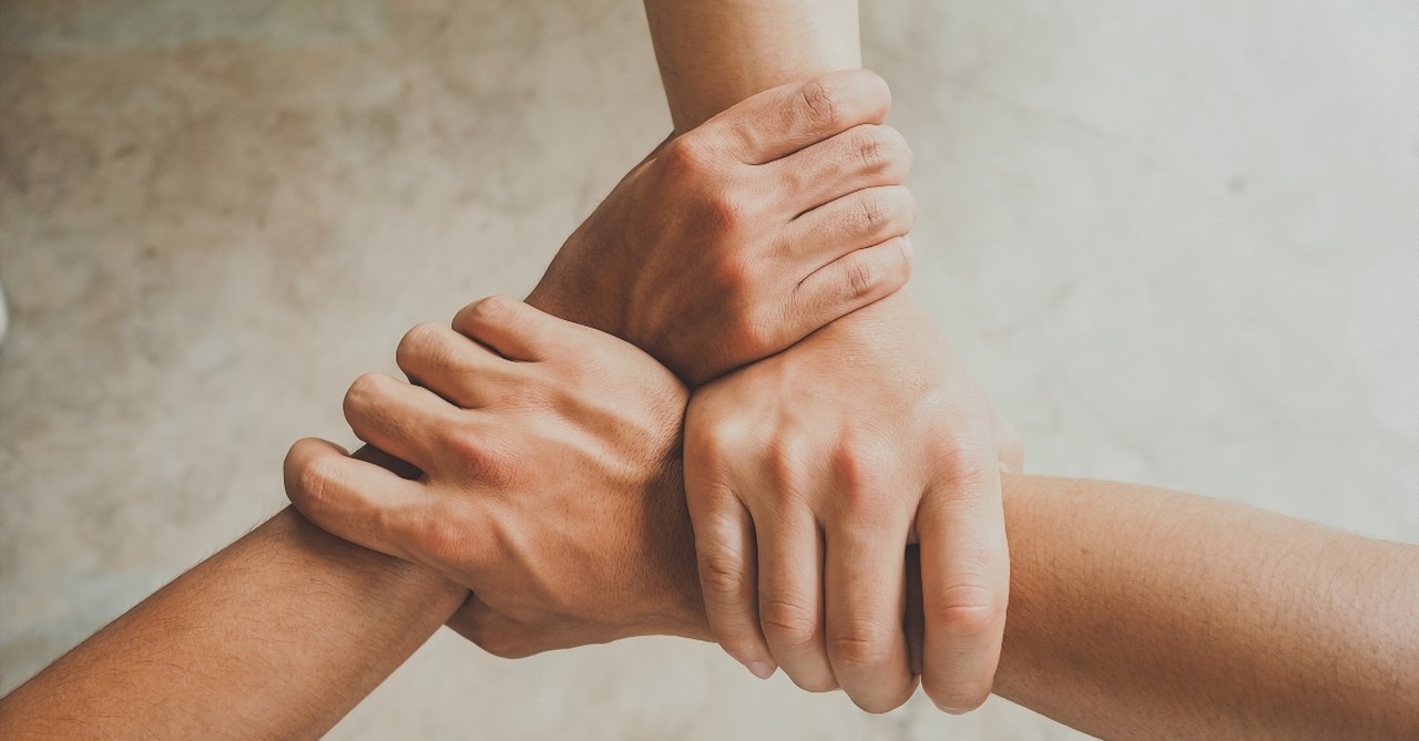 Three hands holding three arms