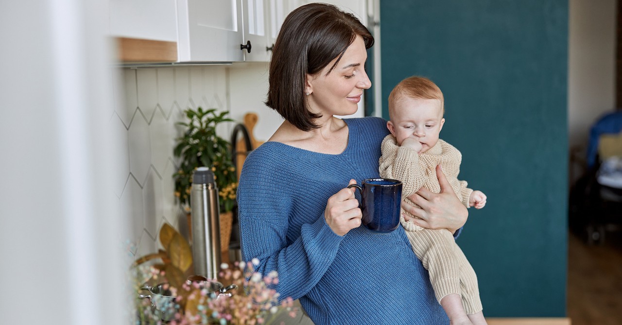 Mom having coffee holding baby in morning