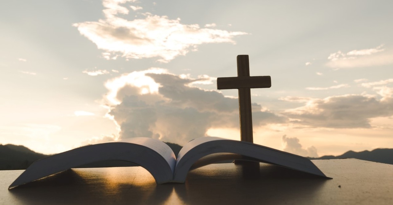 Bible on table with cross and skyline in background