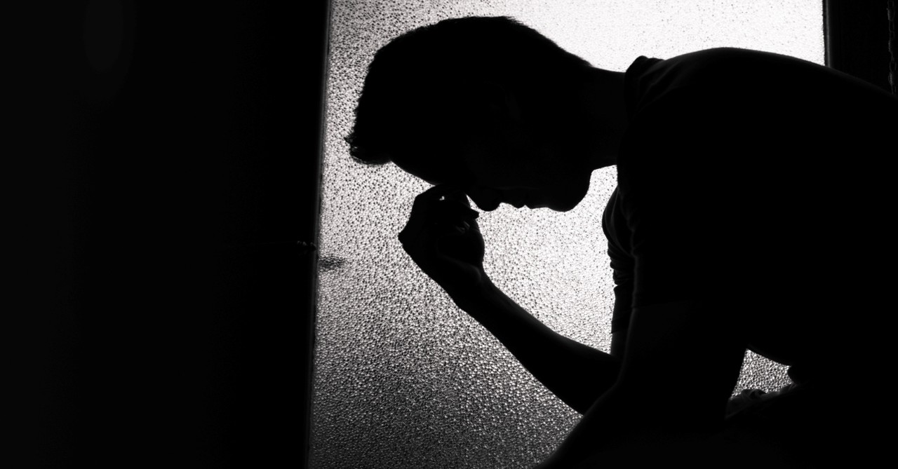 Young sad man sitting in dark room