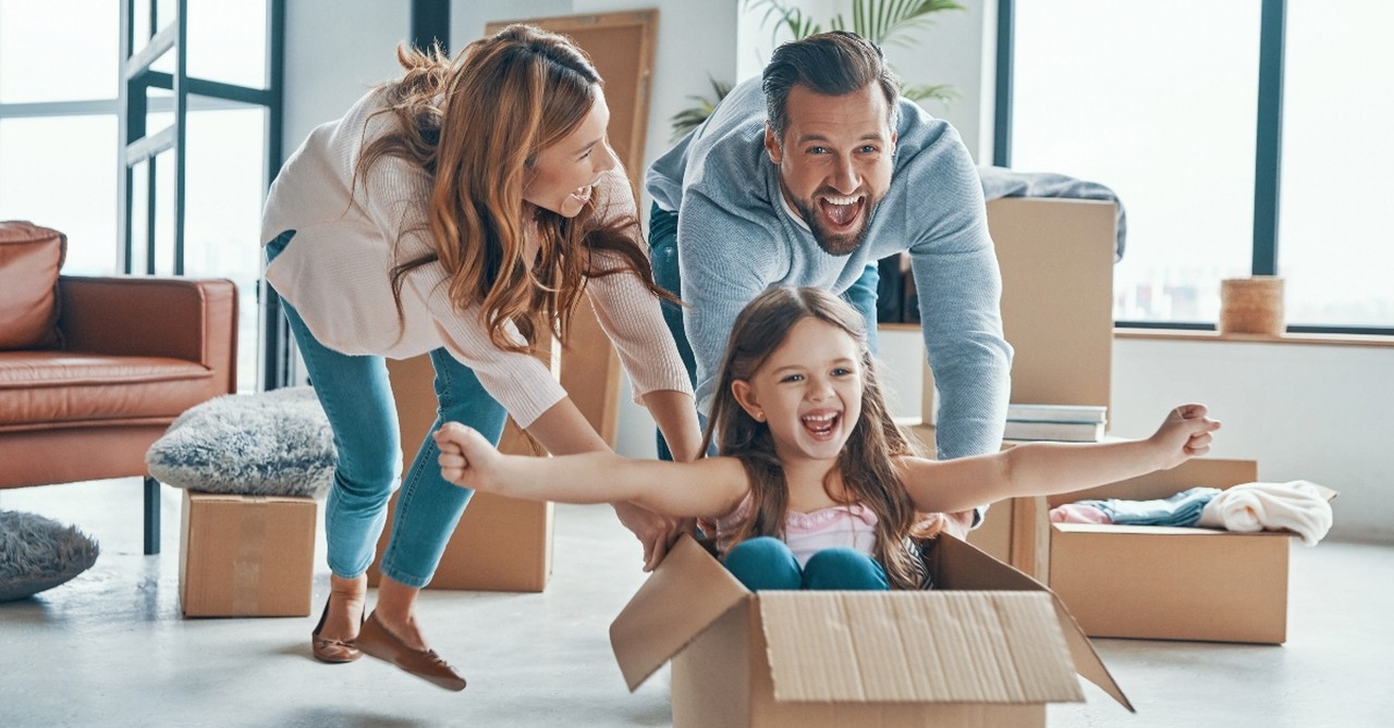 Parents pushing their child in a cardboard box