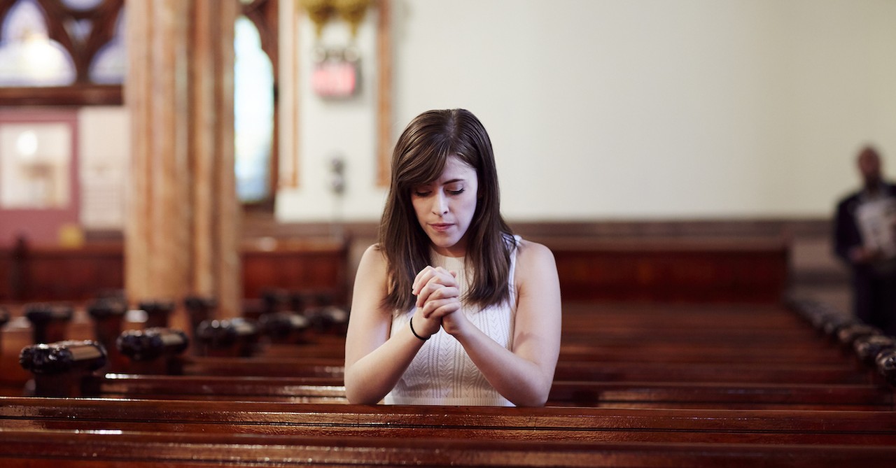 woman praying in church pew for penance