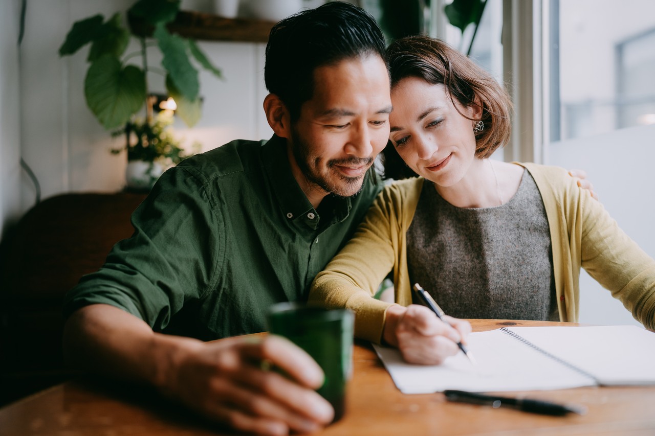 couple sitting close together looking at notepad