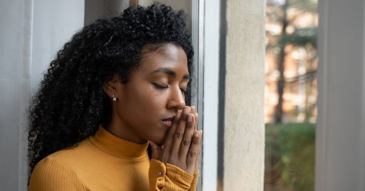 Young woman with eyes closed and hands folded, praying