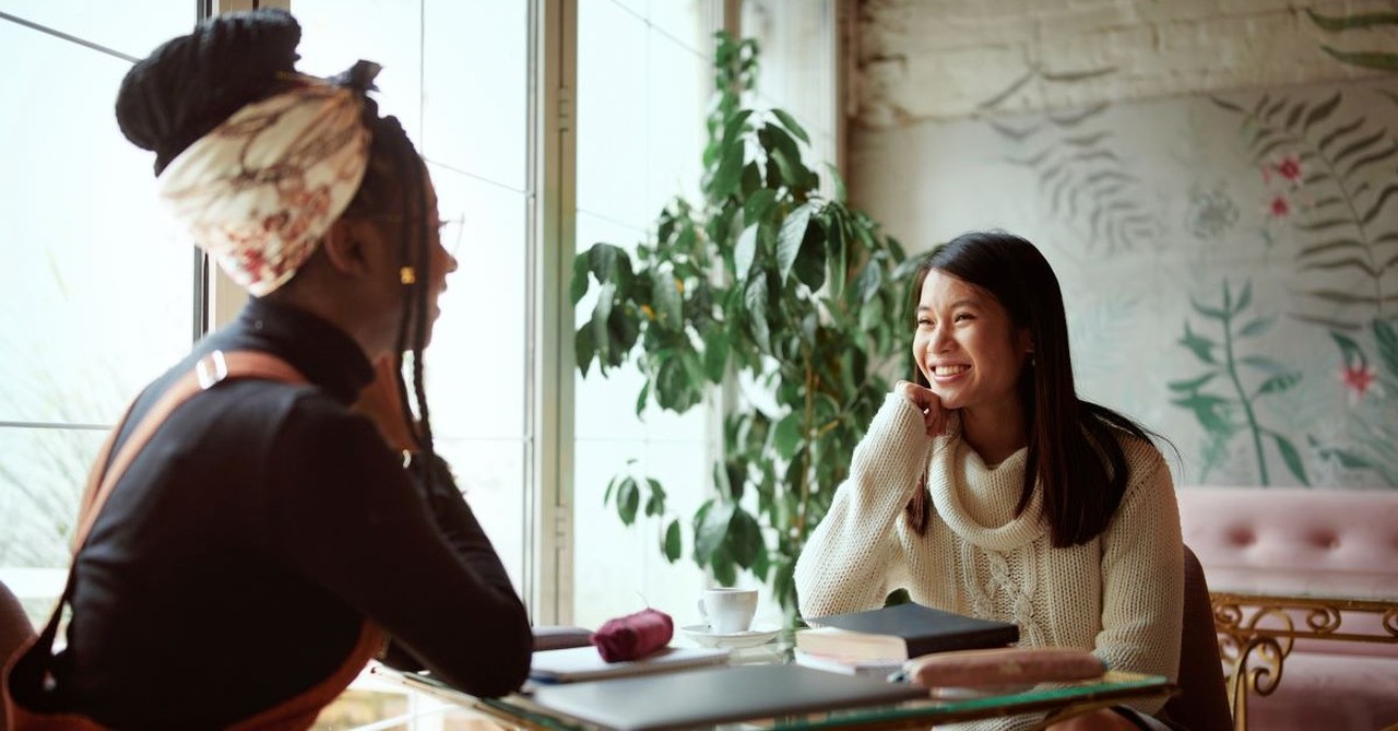 Two young women having a conversation at a coffee shop