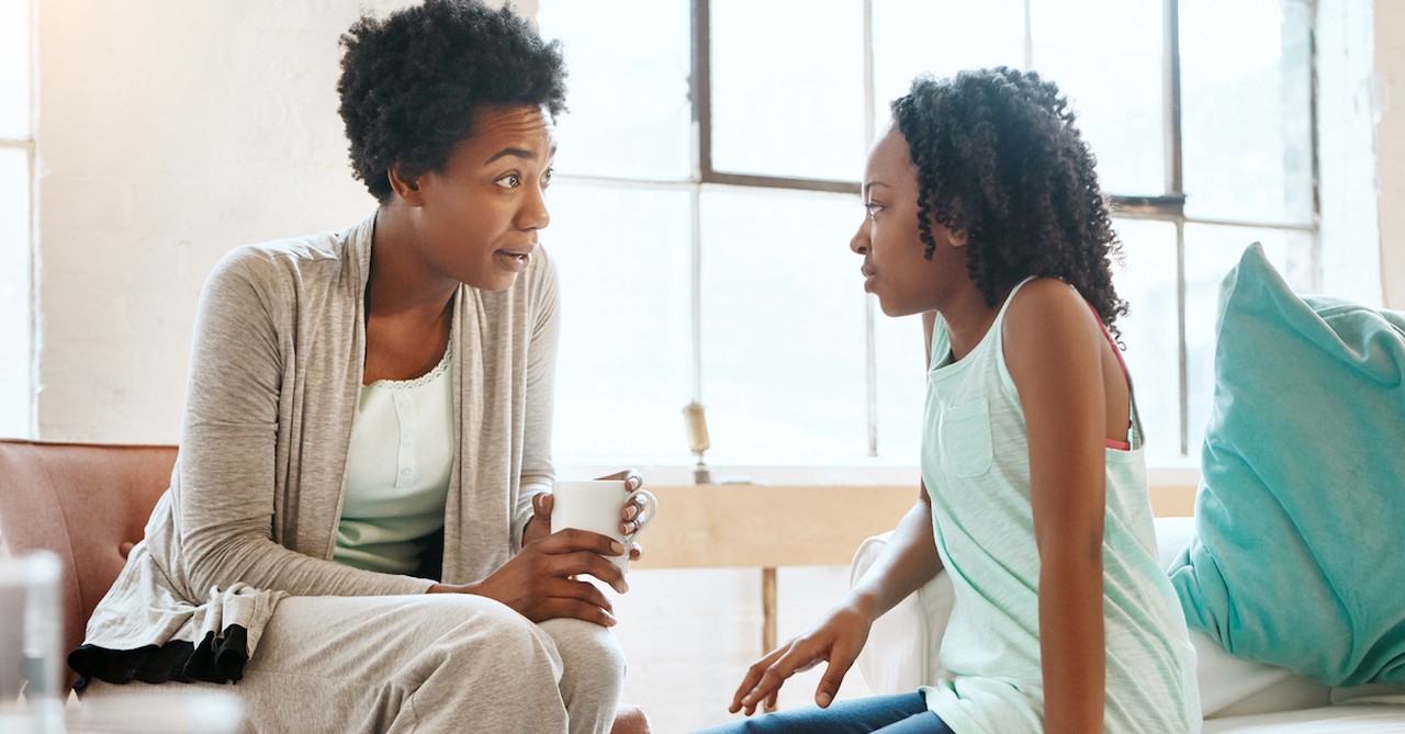 Mom having serious talk with daughter on couch