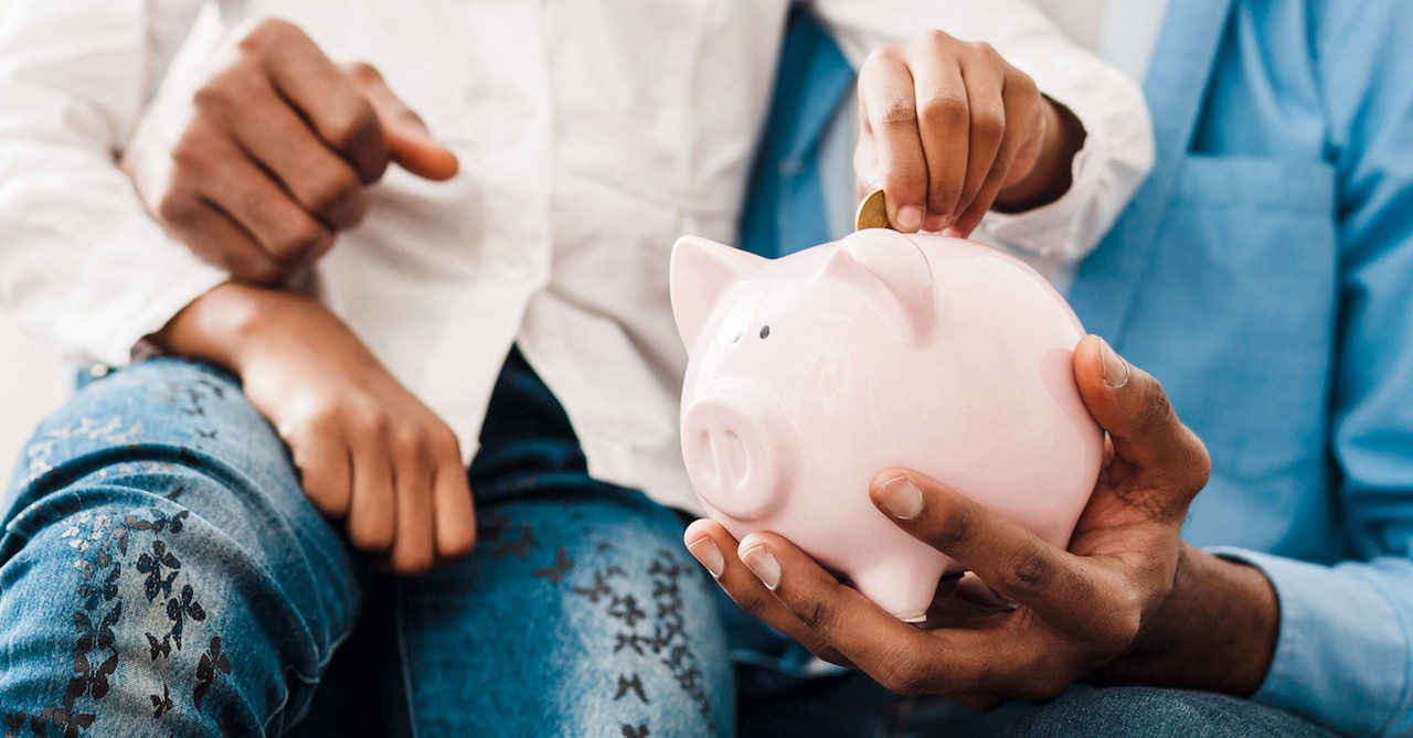 Parent teaching kid to tithe money in piggy bank