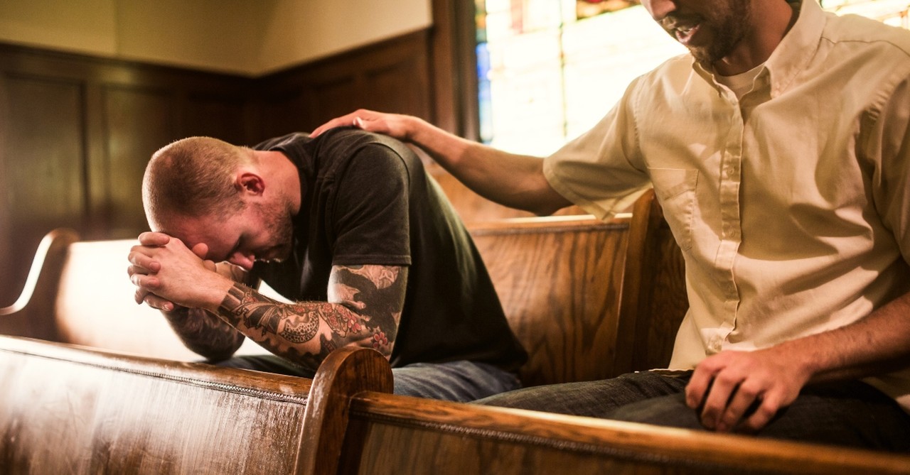 Man comforting another in church