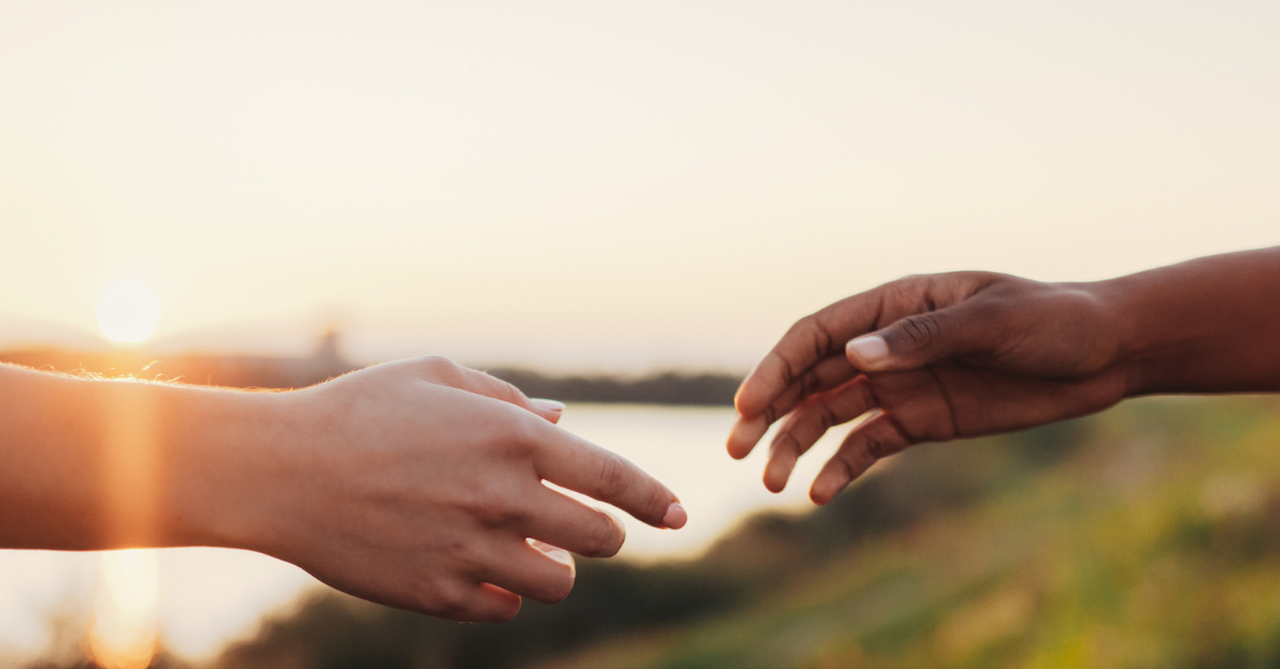Two hands of different color reaching out to each other.