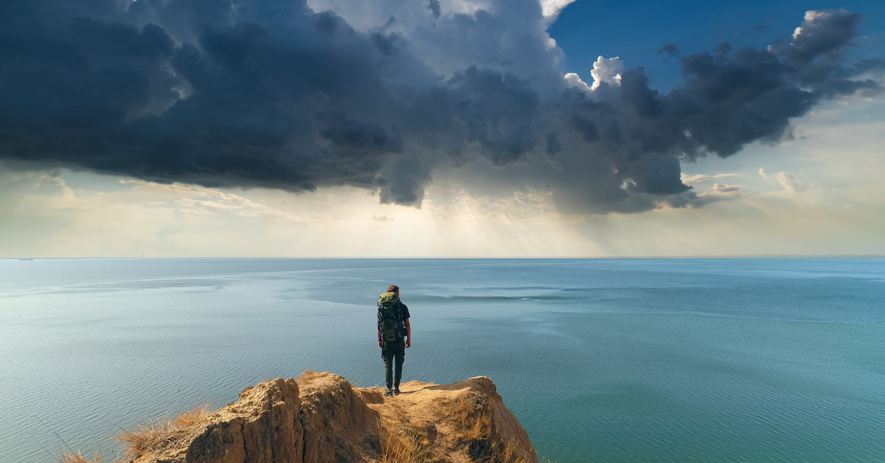 Man standing on a cliff looking out over the water