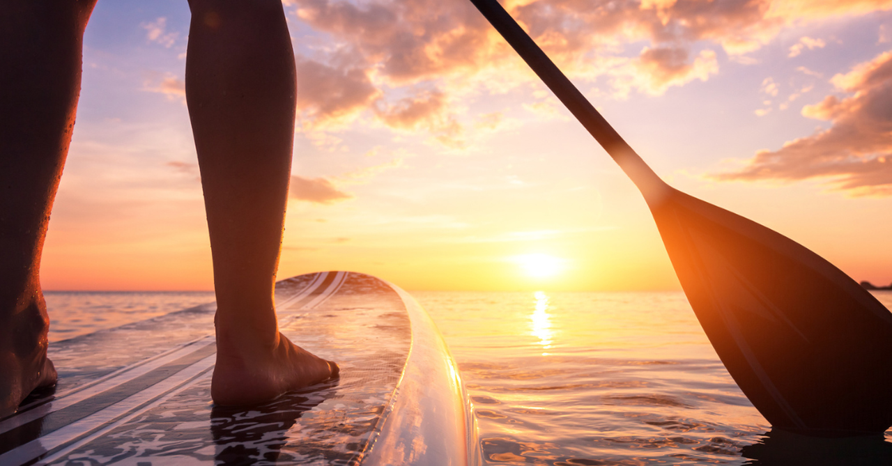 A paddle-boarder on the lake at sunrise.