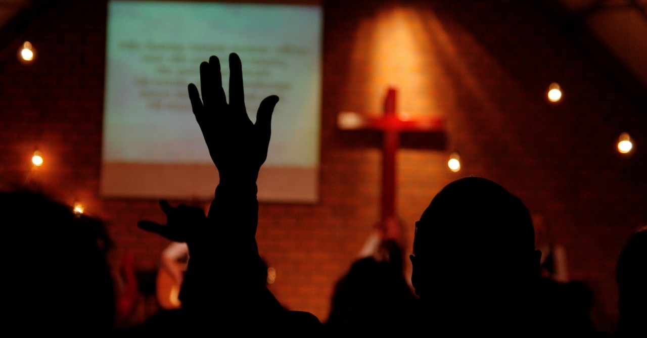 Person raising hands in worship in church