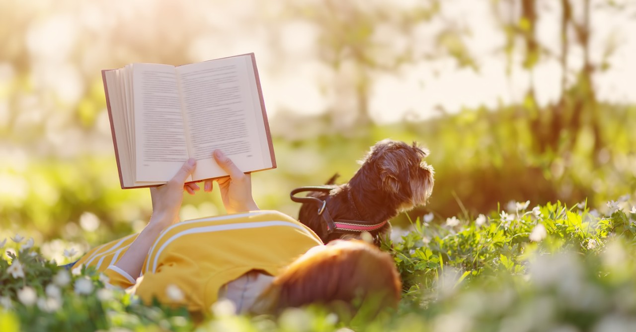 a woman reading in a field of flowers,