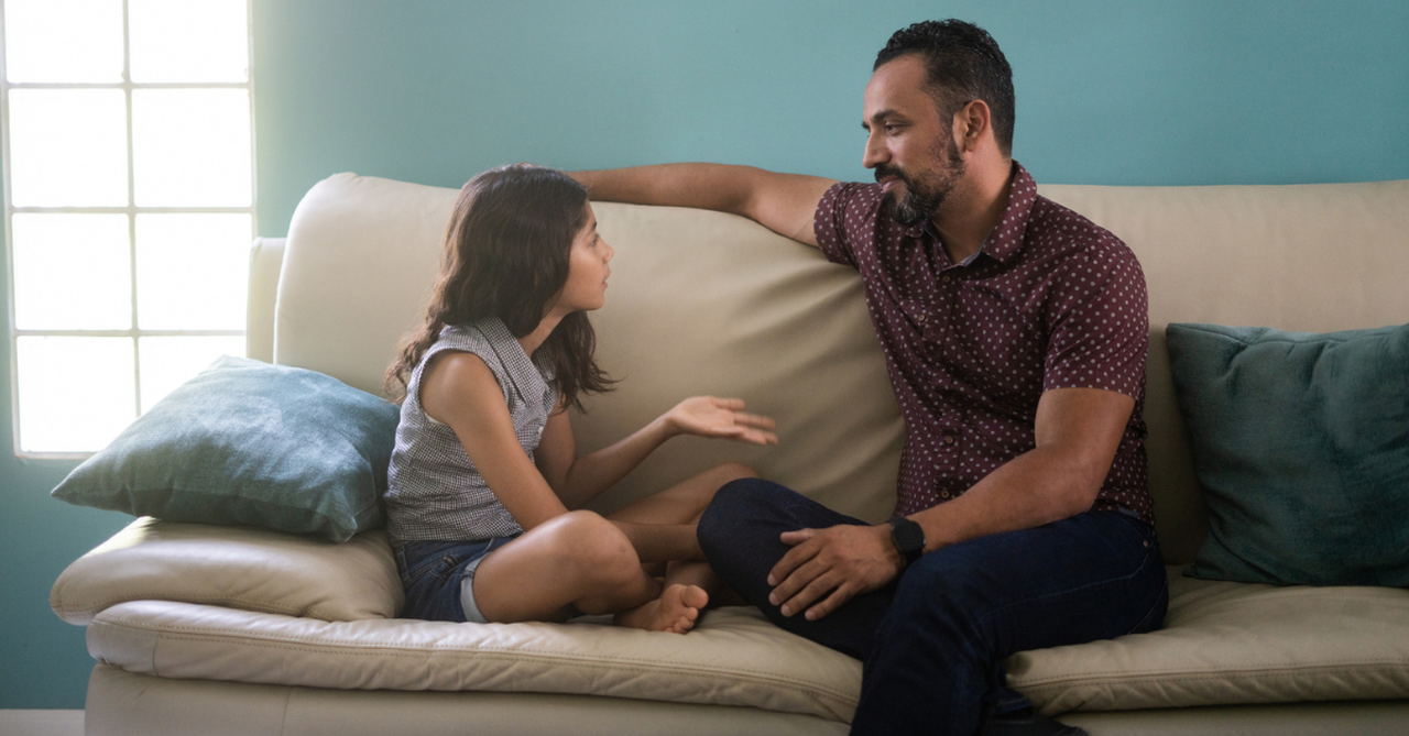 Father and daughter sitting on a couch talking