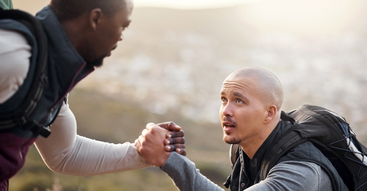 Man helping another man hiking