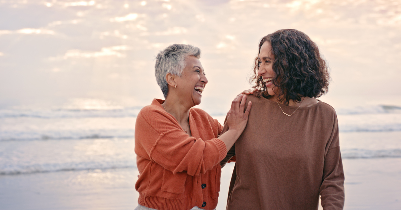 Friends laughing while they walk the beach