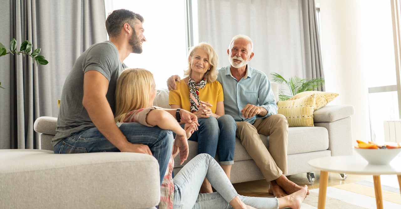 Older senior married couple mentor young couple couch