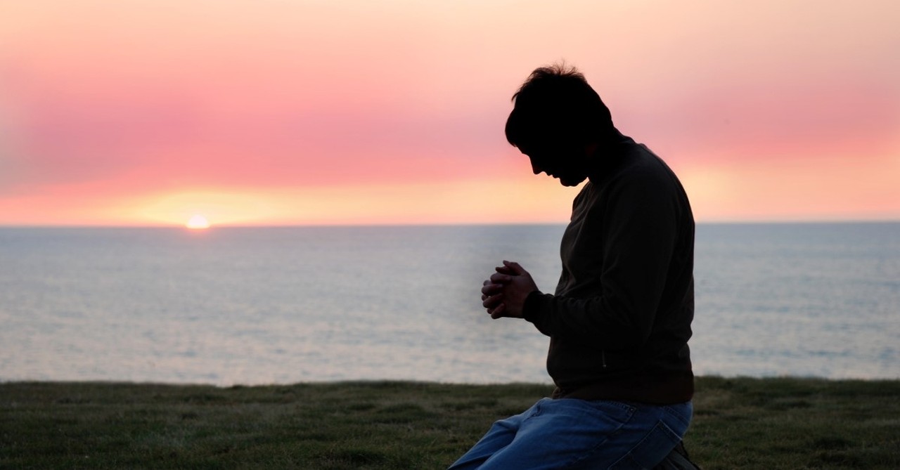 man praying on beach