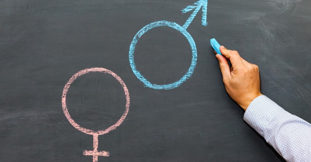 man drawing male and female symbols on chalk board, god and sexuality