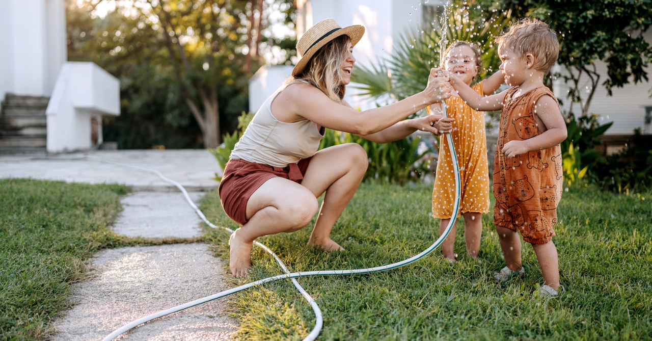 Mom playing in the hose with her toddlers; how I learned to have a stress-free summer with my kids.