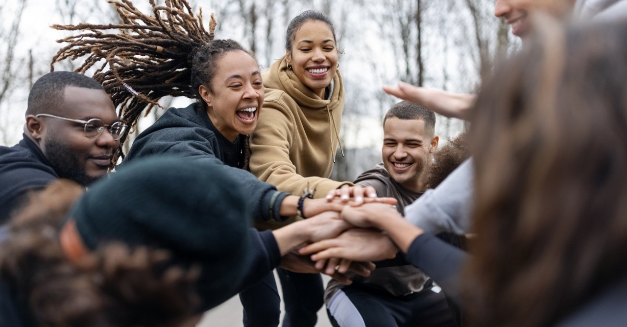 A group of happy people putting hands in the middle