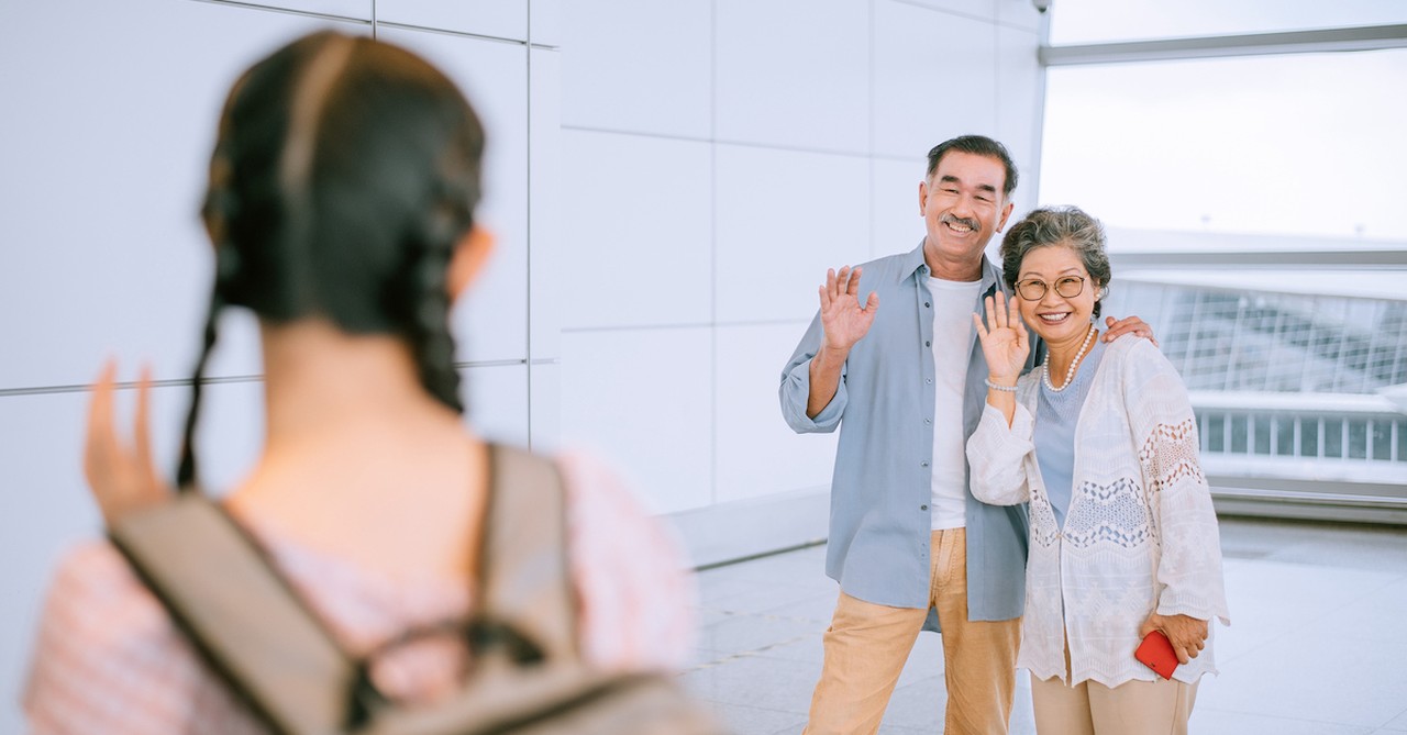 Empty nesters parents waving bye to adult daughter