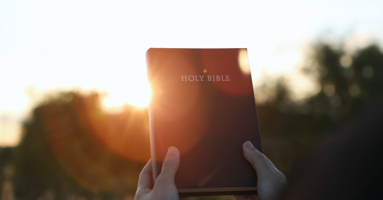 Bible held up in the sunset, trusting in God's Word