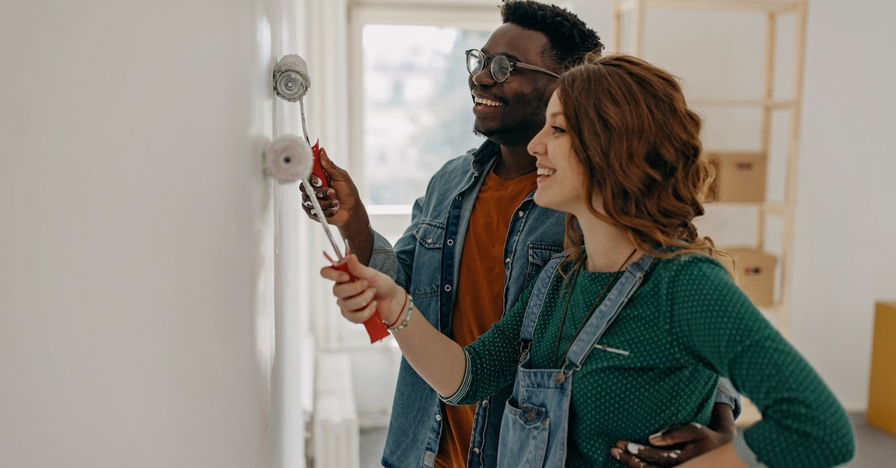 Happy cute married couple painting room