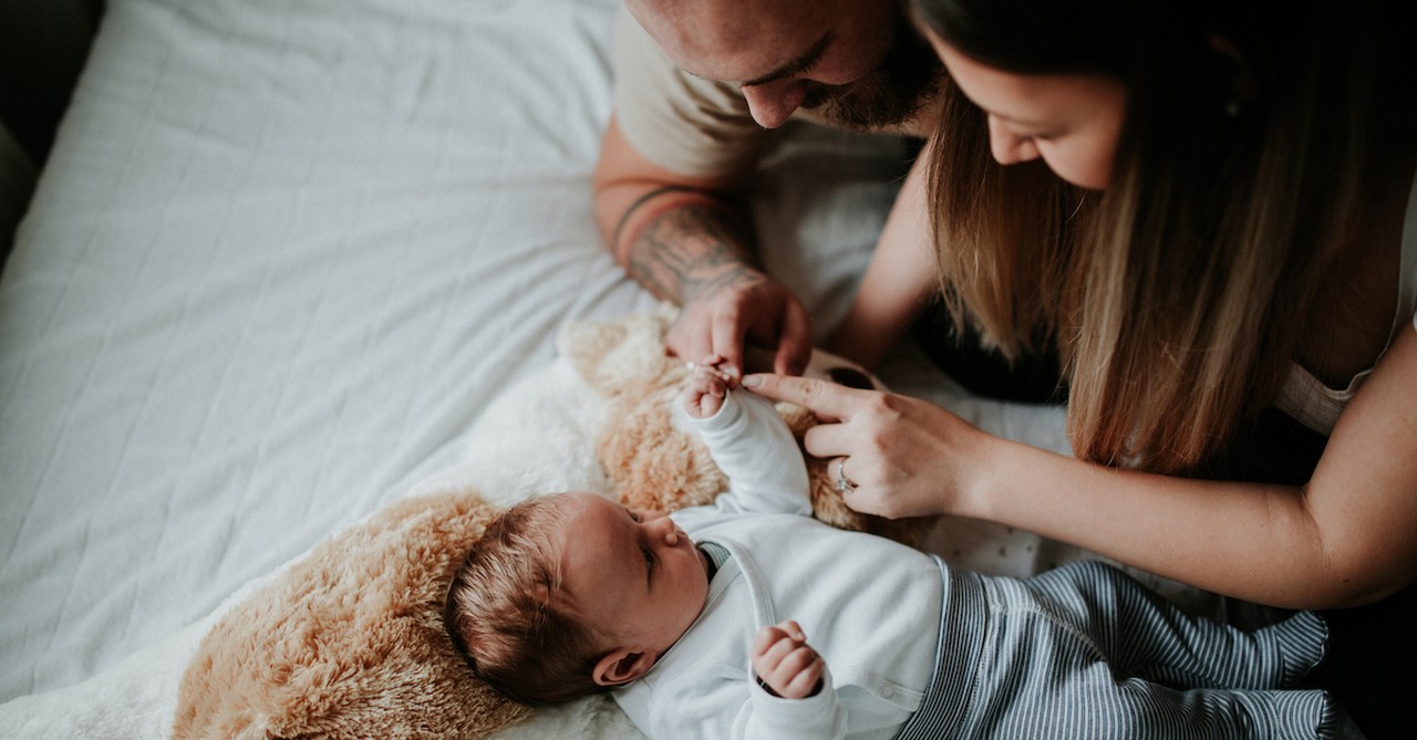 happy couple postpartum on bed with newborn baby