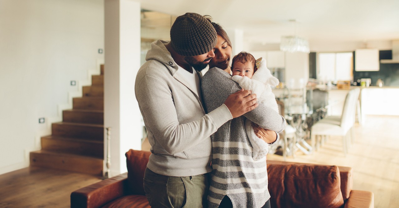 Happy couple family holding newborn baby in house