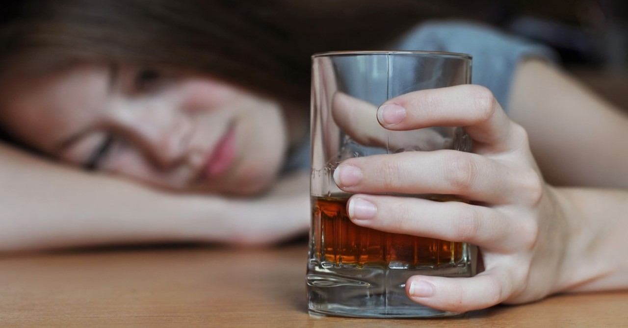 drunk woman holding glass of whiskey, illustration for article on what does the bible say about drunkenness