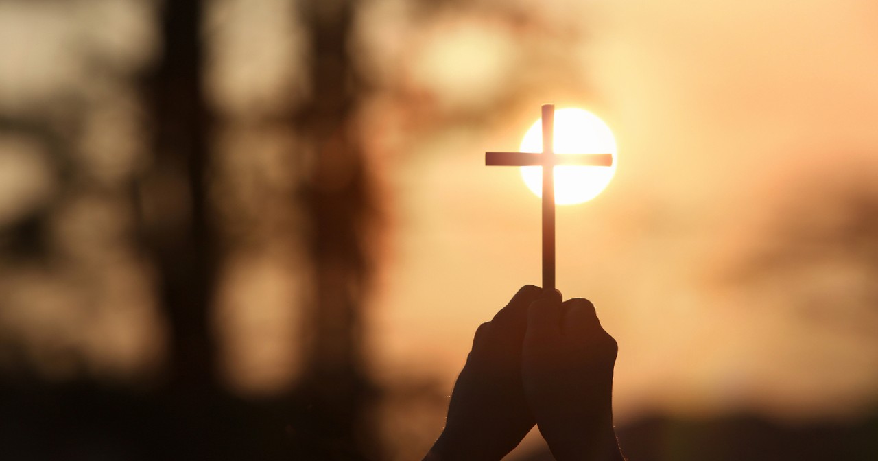 hands holding up a cross