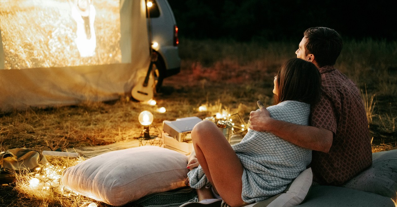 Couple watching cozy movie in fall outside projector