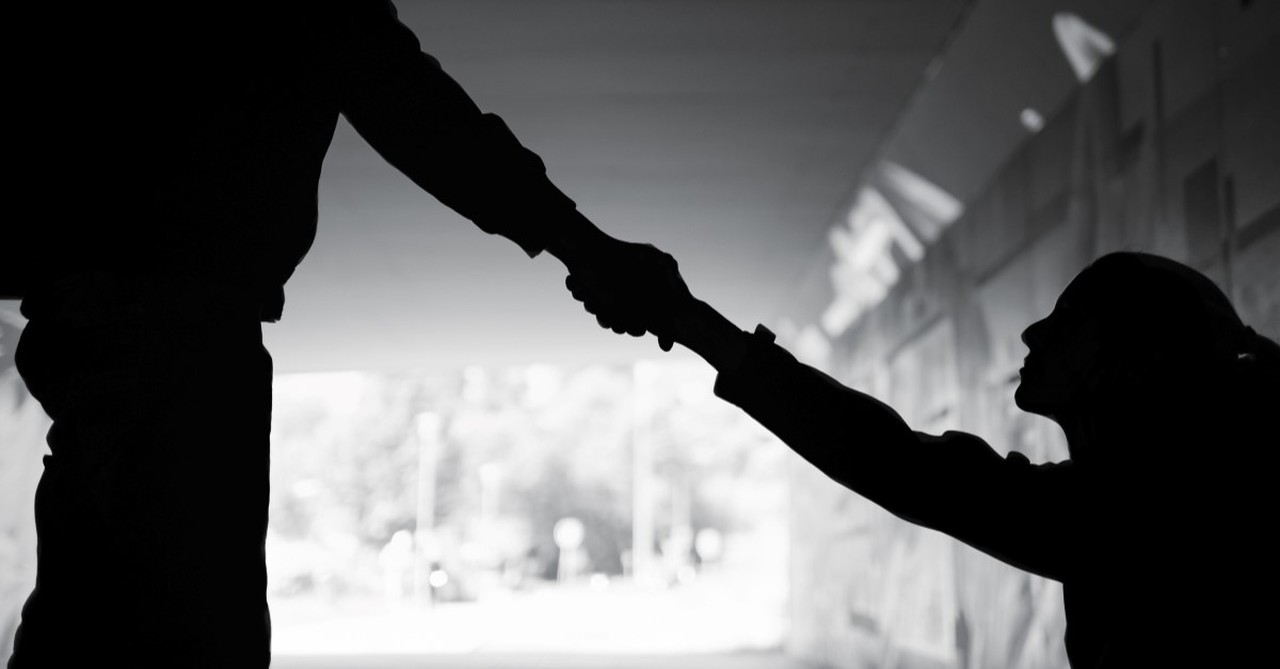 man giving helping hand to person under bridge to illustrate golden rule