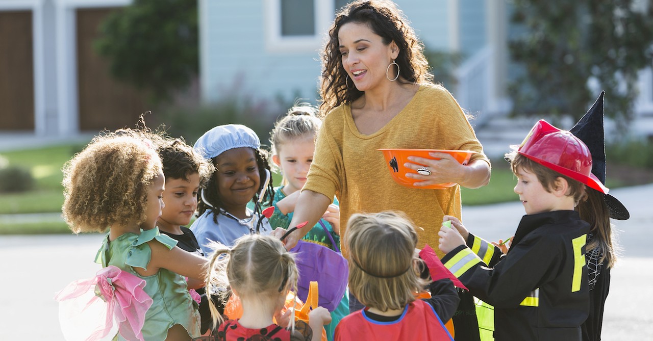 woman handing out halloween candy at trick or treat to kids