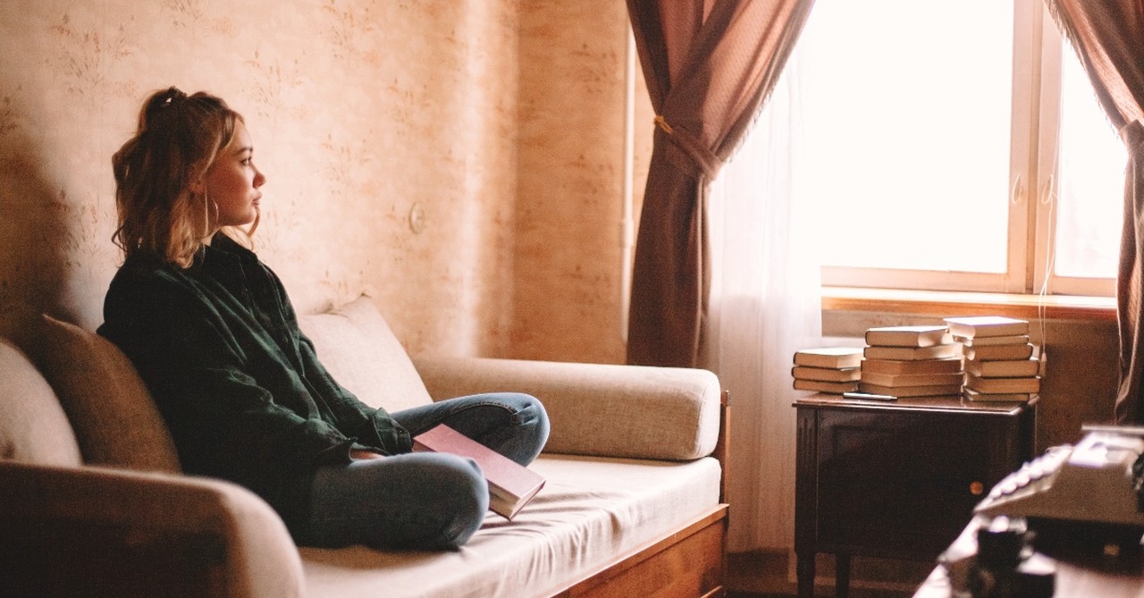 Woman looking bored with a book on her lap on a couch