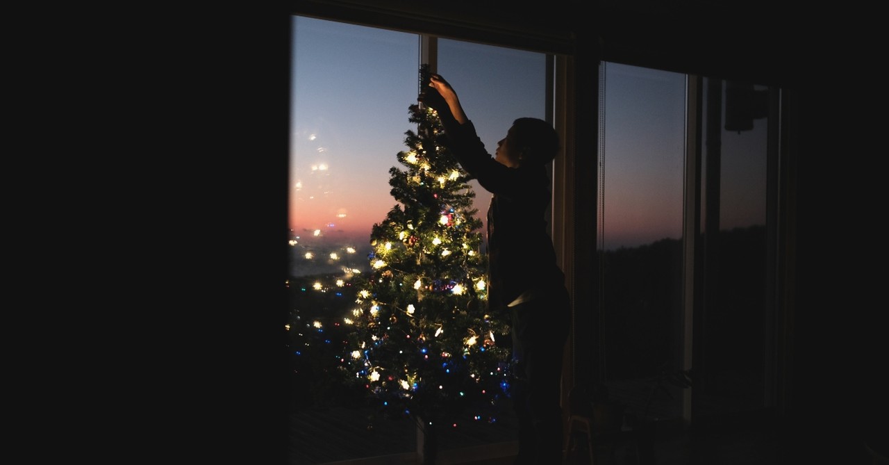 Man putting lights on a Christmas tree