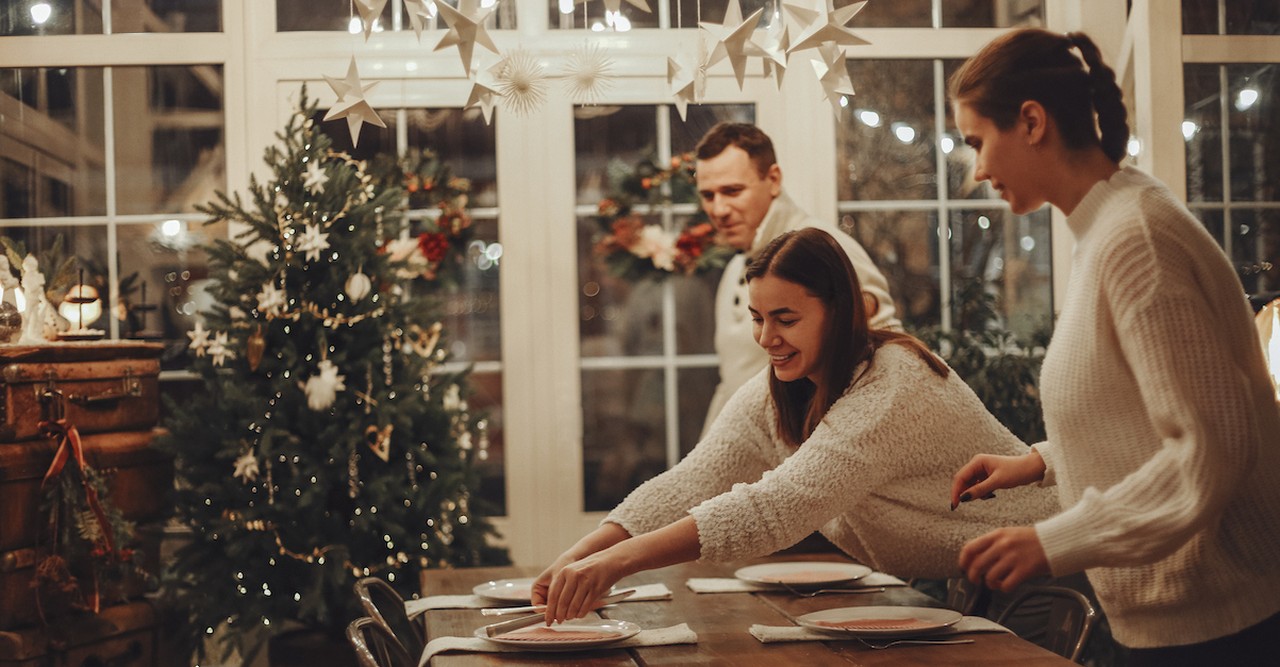 Couple and friends decorating for hosting Christmas party dinner