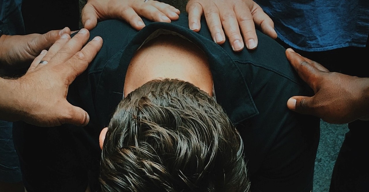 men praying over pastor