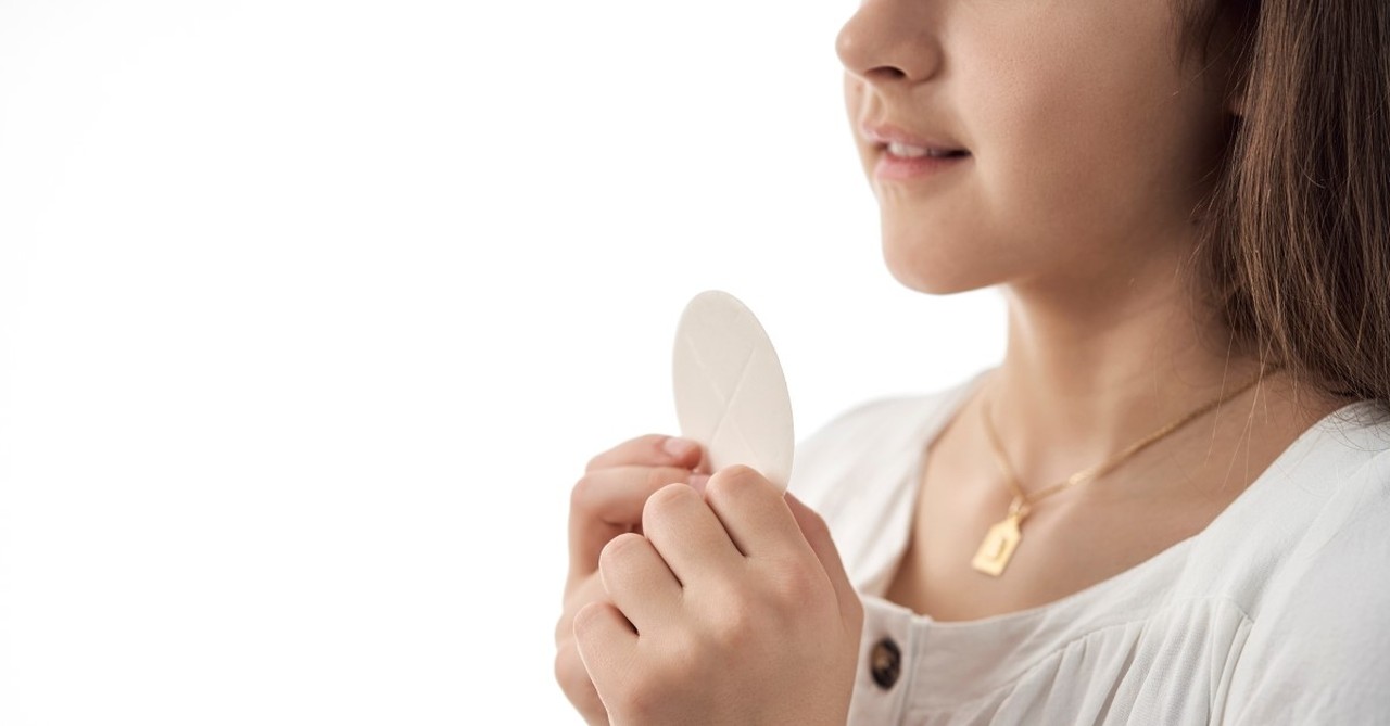 little girl in white dress holding communion wafer