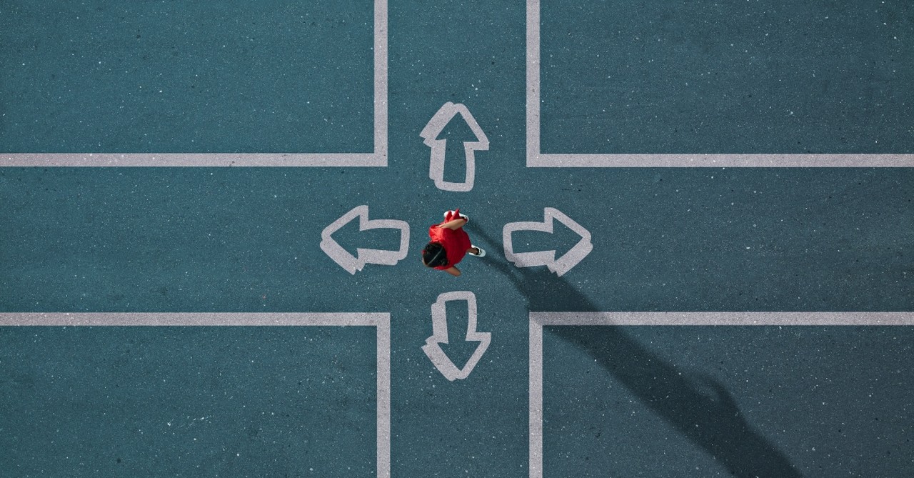 Person standing at a 4-way cross, with arrows pointing in each direction