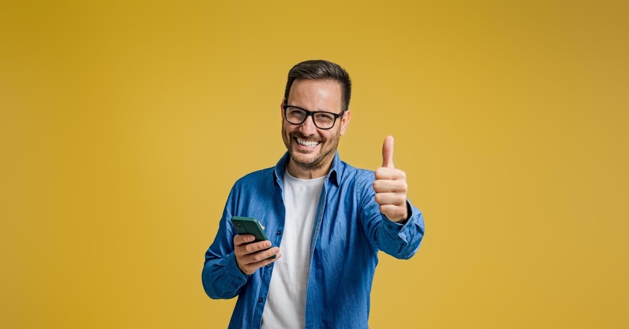 smiling man giving thumbs up sign, signs you are seeking the approval of others