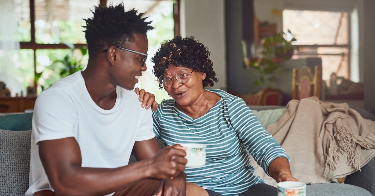 adult son talking with senior mom on couch with coffee