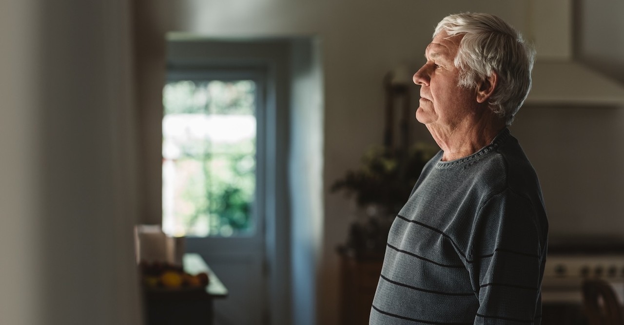 Senior man widower sad thinking looking out window grief