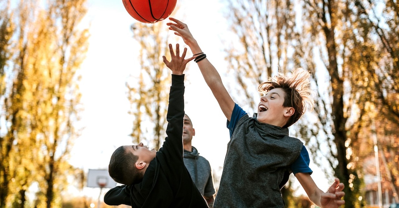 Brothers outside playing basketball competitive rivalry