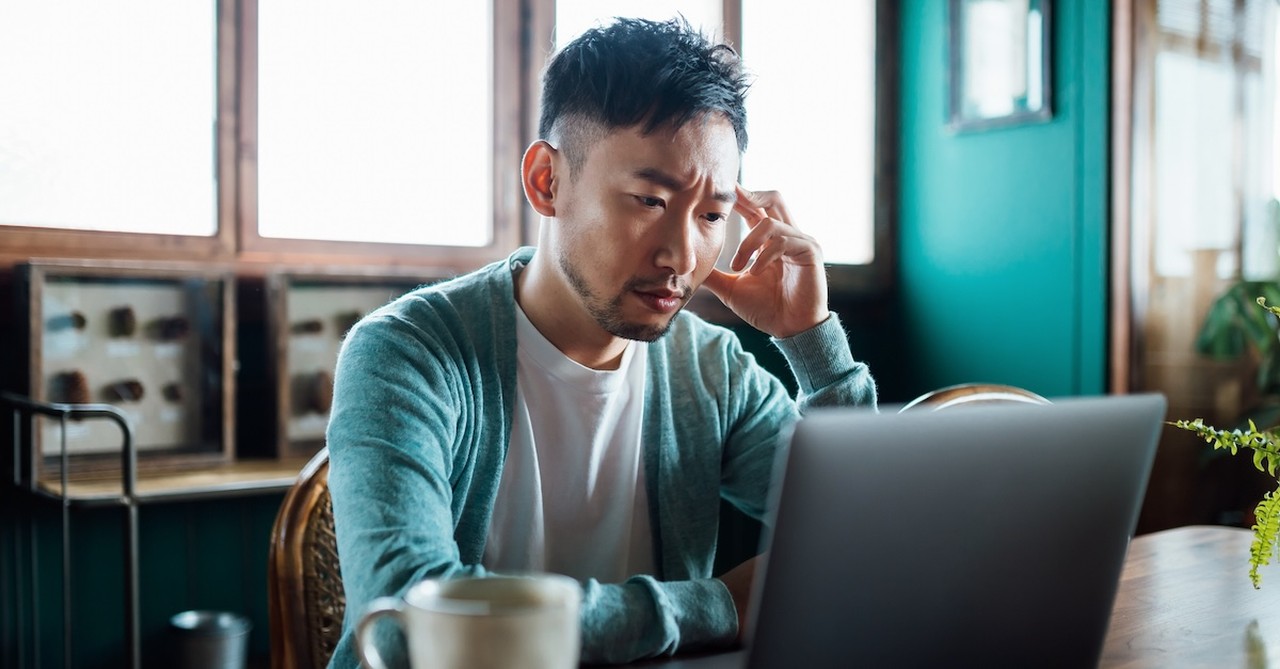 Asian man on laptop stressed burnt out working remote